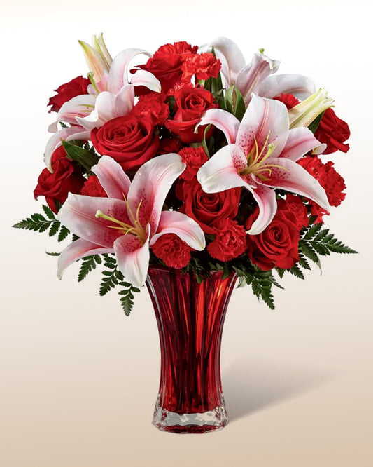 A refined bouquet of roses, carnations, and lilies in a modern red vase. Delivered worldwide by trusted local florists.